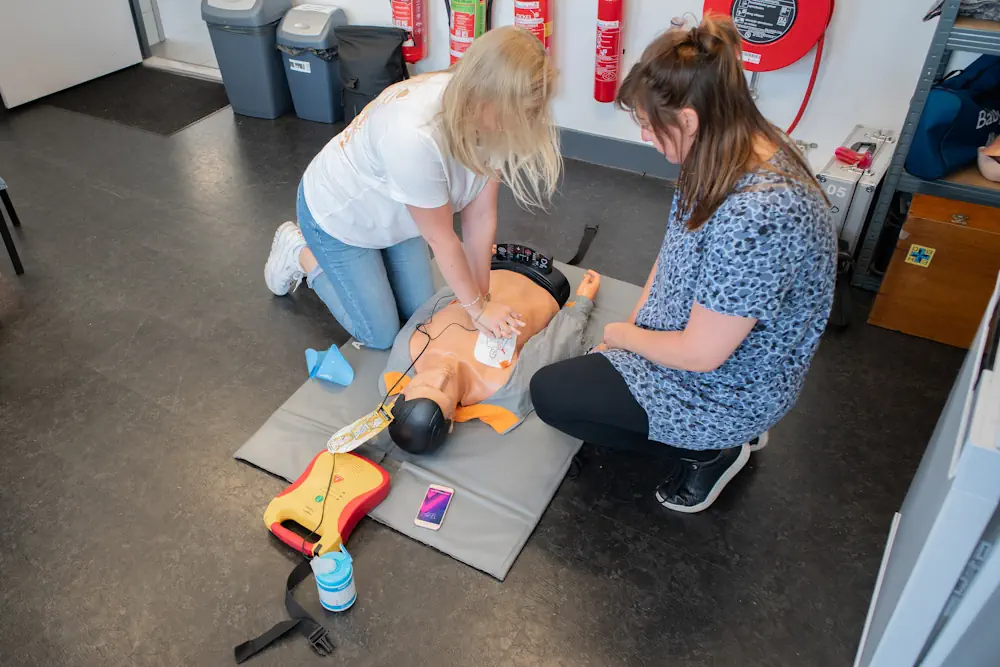 Twee vrouwen oefenen reanimatie op een mannequin bij de EHBO Cursus van BHV Noord Nederland.